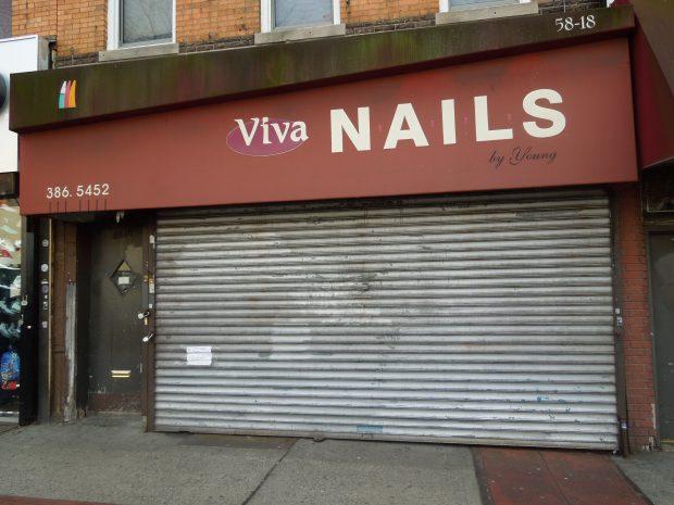 A closed nail salon with a brown metal roller shutter. The salon's sign above reads "Viva Nails by Young" with a phone number "386-5452." The building facade appears aged, with some discoloration at the top. The entrance door is to the left of the shutter.